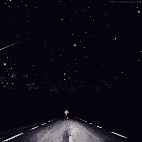 a person is driving down a road at night with a shooting star in the background