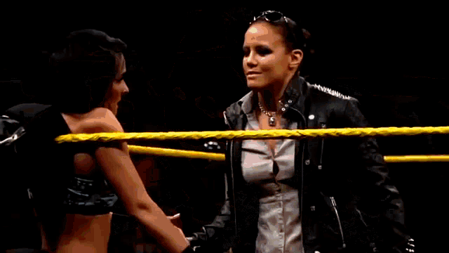 two women are wrestling in a ring and one of them is holding the other woman 's waist .