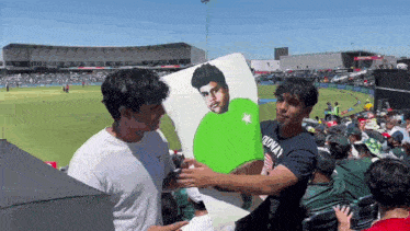 a man wearing a t-shirt that says oldway holds a picture of a man