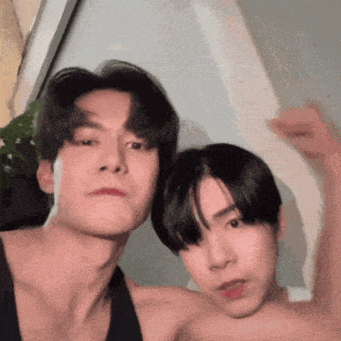 two young men are posing for a picture together and one of them is flexing his arm .
