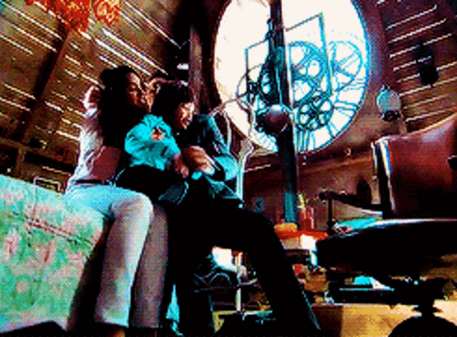 a couple sitting on a couch in front of a clock