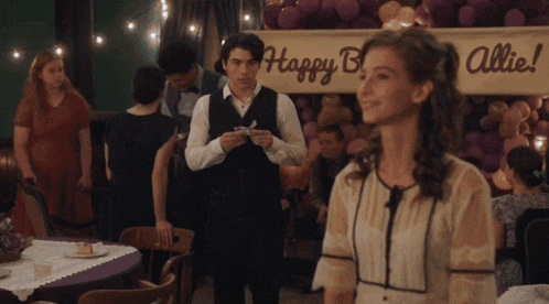 a woman stands in front of a happy birthday sign