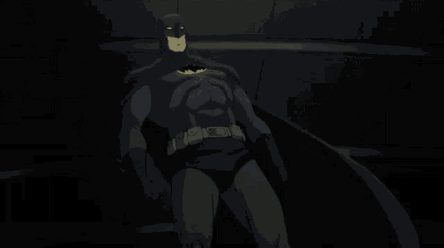 a man in a batman costume stands in the dark