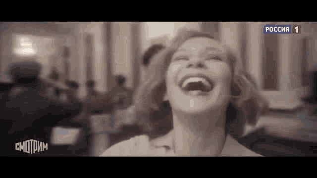 a woman is laughing in a black and white photo with her mouth open .