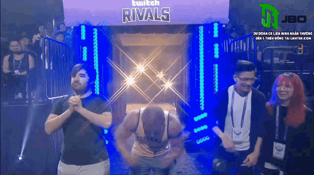 a group of people standing in front of a twitch rivals sign