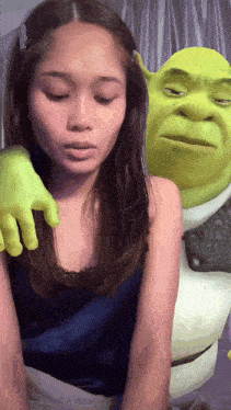 a woman is being touched by shrek 's green hand