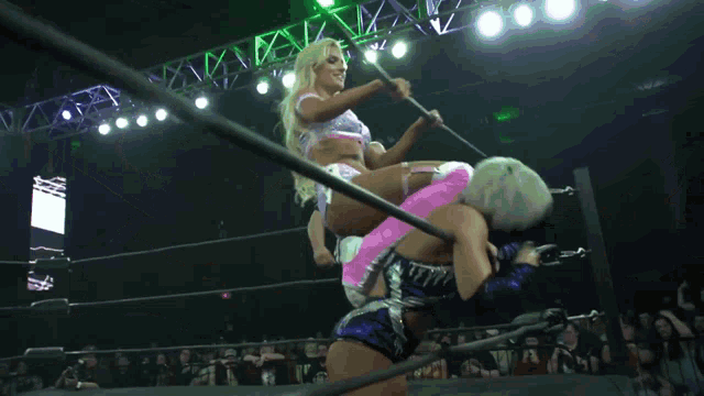 a woman in a wrestling ring with a referee behind her