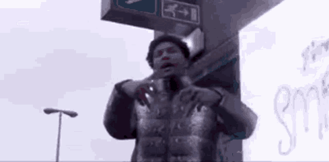a man in a jacket is standing in front of a billboard .