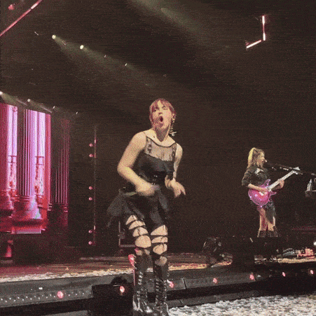 a woman in a black dress is singing on stage