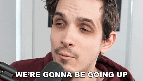 a man talking into a microphone with the words " we 're gonna be going up " above him