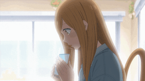 a girl with long brown hair is drinking from a blue cup