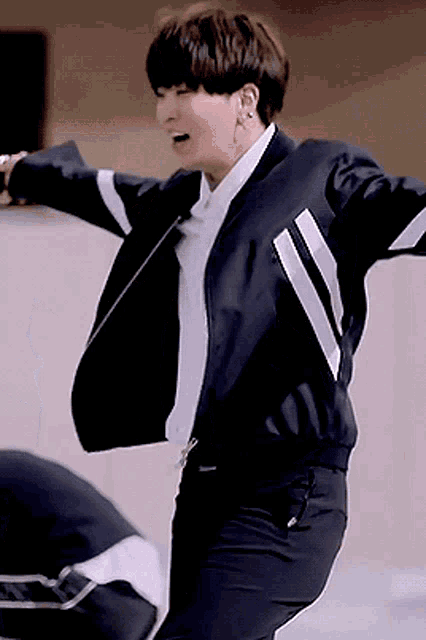 a young man in a black jacket and white shirt is dancing