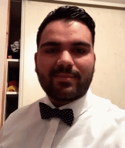 a man with a beard wearing a white shirt and black bow tie