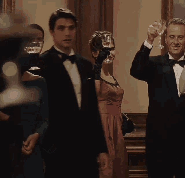 a man in a tuxedo holds a glass of champagne