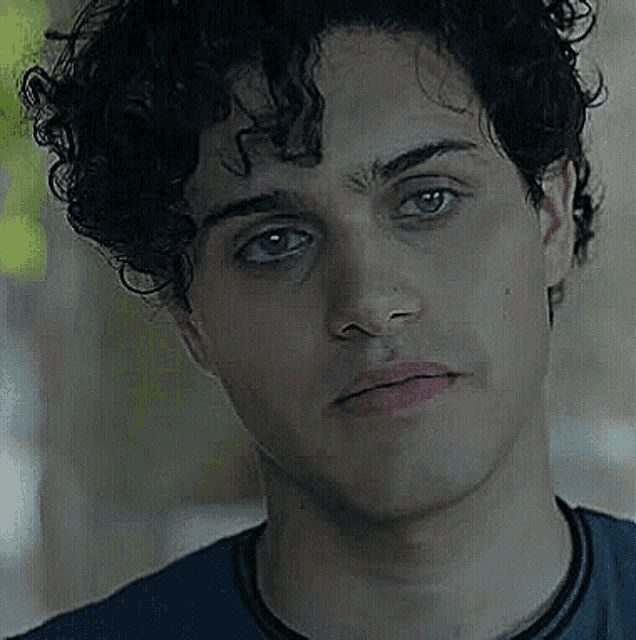 a close up of a man 's face with curly hair and a serious look on his face .