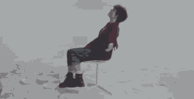 a person is sitting on a chair in the snow with their legs outstretched .