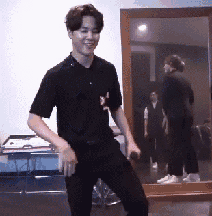 a young man in a black shirt is dancing in front of a mirror