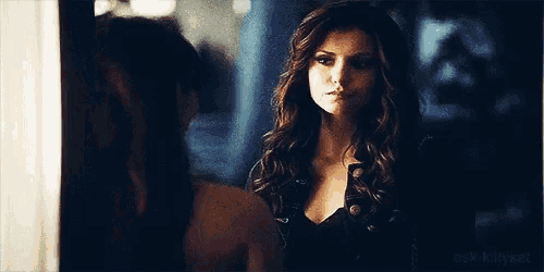 a woman is standing in front of a mirror and looking at herself .