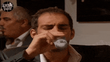 a man drinking from a glass with the words kurtlar vadisi on the bottom right