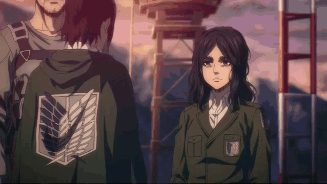 a man and a woman are standing next to each other and the woman is wearing a green jacket with wings on the back