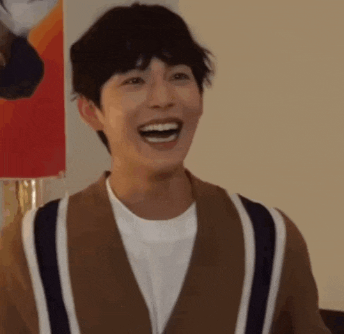 a young man is laughing with his mouth open and wearing a brown and white striped sweater .