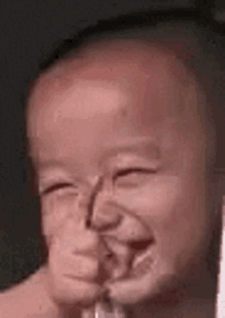 a baby is smiling with his eyes closed and his mouth open .