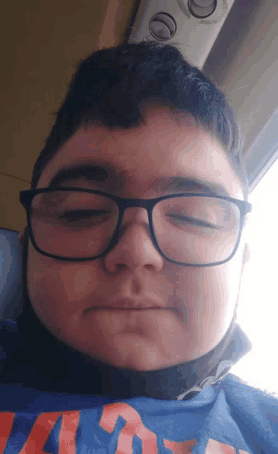 a boy wearing glasses and a blue shirt that says ' a ' on it