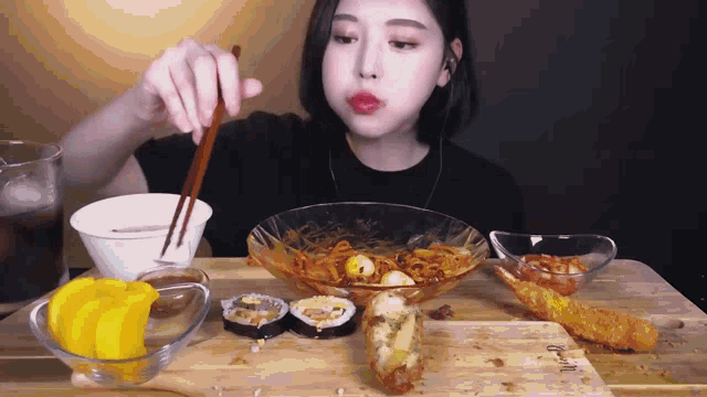 a woman is sitting at a table with chopsticks eating food