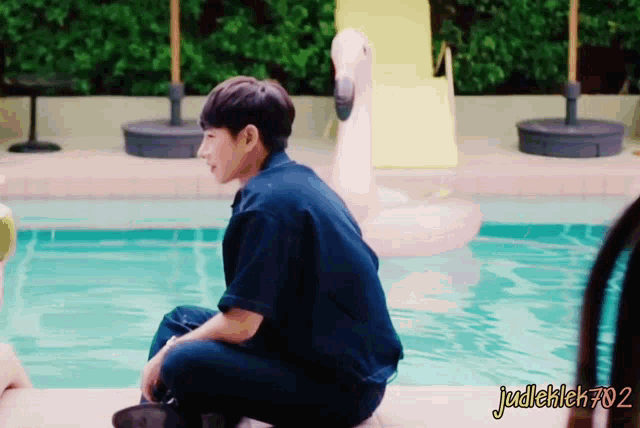 a man sits on the edge of a swimming pool with the watermark judlekleh702