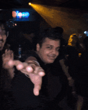 a man reaches out his hand in front of a sign that says dj