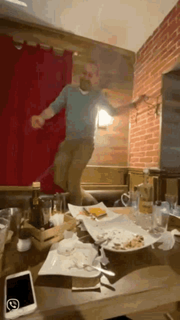 a man is jumping in the air in front of a table full of plates and glasses