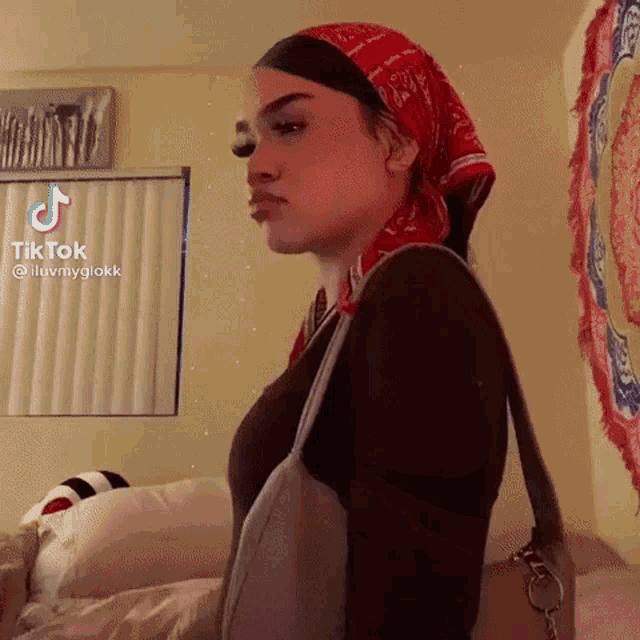 a woman wearing a bandana and a purse is standing in front of a mirror .