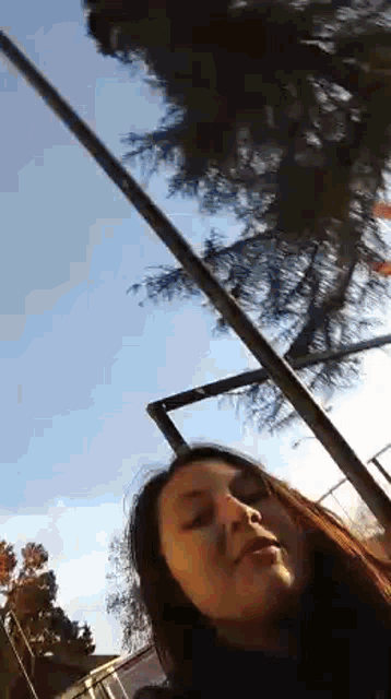 a woman is standing in front of a tree and looking up at it