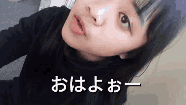 a girl with purple hair is taking a selfie with chinese writing on the bottom of her face .