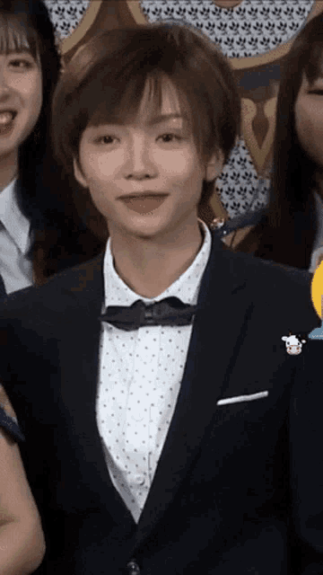 a woman wearing a suit and bow tie is smiling