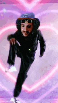 a man wearing a hat with the letter m on it stands in front of a pink heart