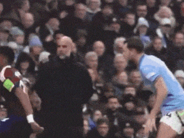 a referee stands between two soccer players in front of a crowd of people .