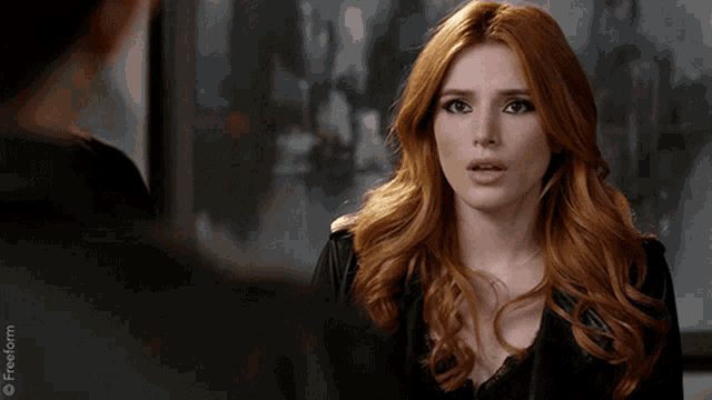 a woman with red hair is talking to a man in a black jacket