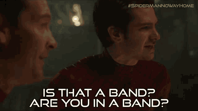 a man in a red shirt is talking to another man in a dark room .