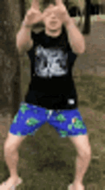 a man in a black shirt and blue shorts is standing on his knees in the grass .