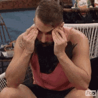 a man with a beard is sitting on a chair with his eyes closed .