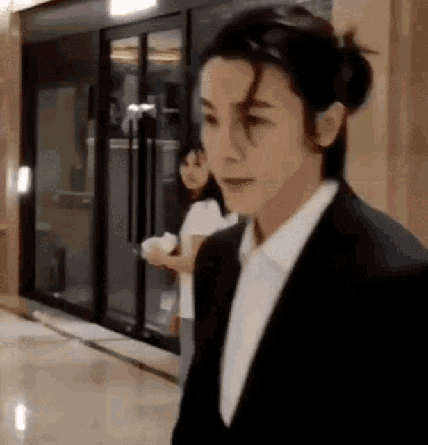 a man in a suit and tie is walking down a hallway next to a woman .