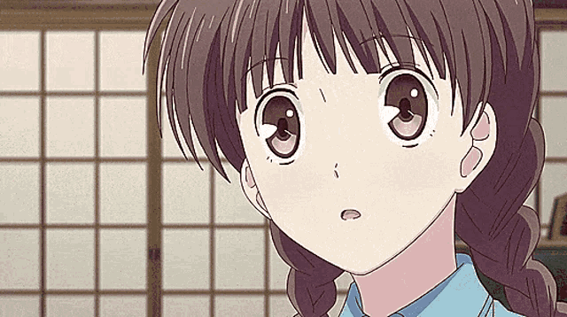 a close up of a girl with braids and a blue shirt looking up .