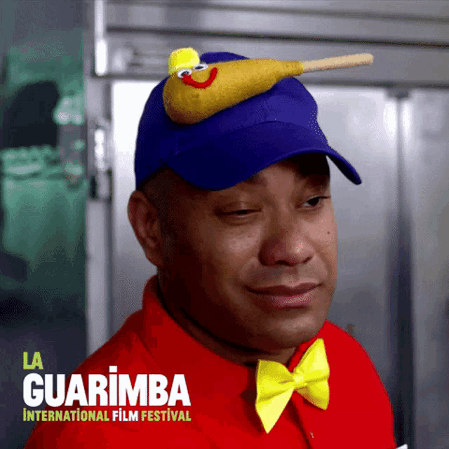 a man wearing a blue hat and a yellow bow tie is advertising la guarimba international film festival