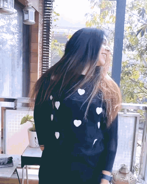 a woman with long hair wearing a black sweater with white hearts