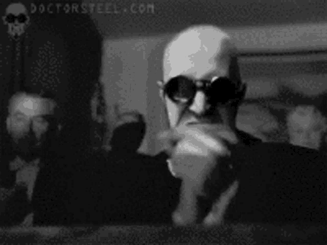 a black and white photo of a man wearing sunglasses and a suit .