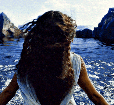 a woman with long hair is standing in the ocean