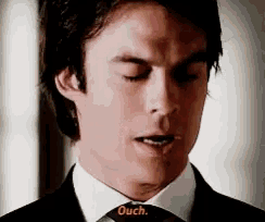 a close up of a man 's face with the word ouch in yellow