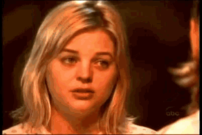 a close up of a woman 's face with a man 's arm behind her .