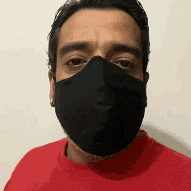 a man wearing a red shirt and a black mask